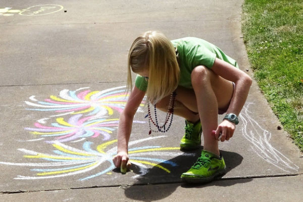 Child drawing on pavement with chalk