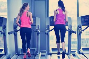 Two ladies talking on treadmills in gym